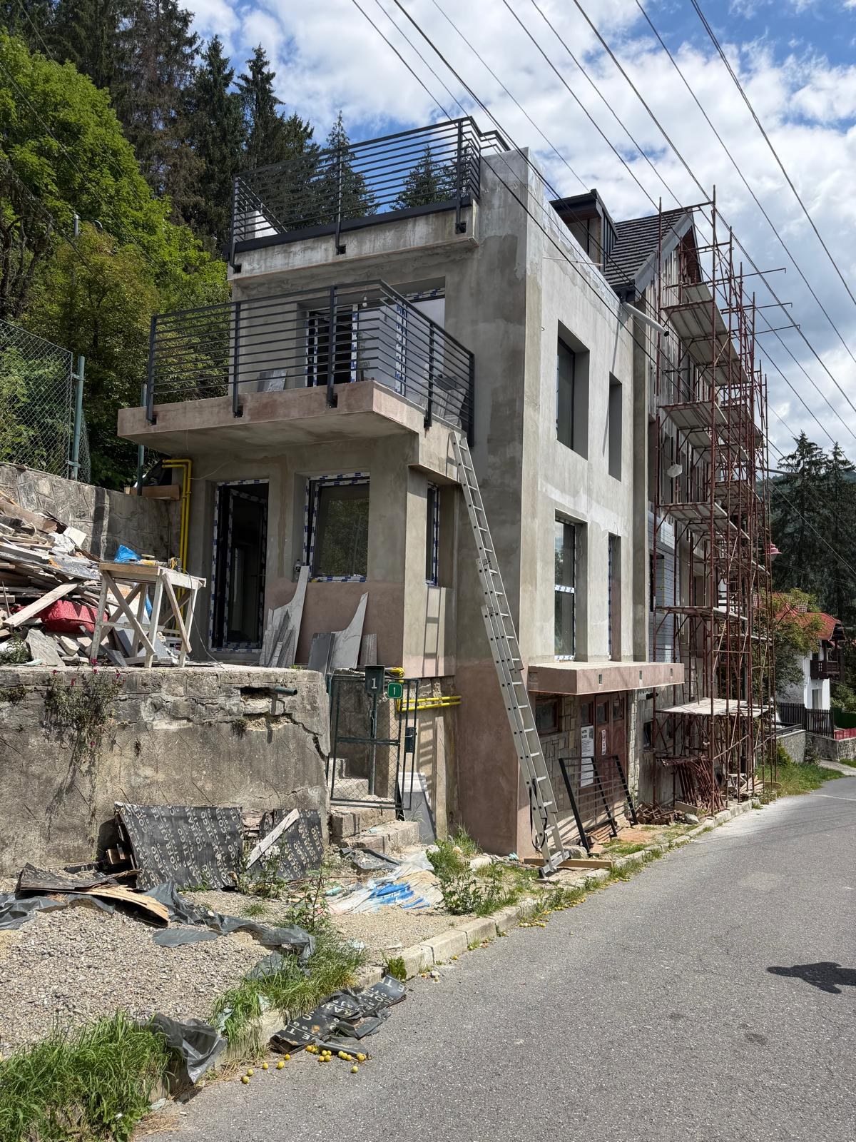 Vilă montană cu două balustrade metalice negre montate pe terase suprapuse